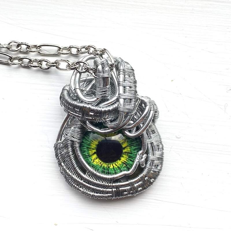 A woven wire wrapped silver necklace with a green eye focal.