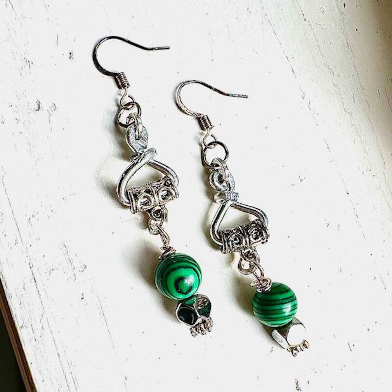 Faux malachite drop earrings. There is a hand wrought aluminum component where a pewter bail is utilized to drop the faux malachite. The faux malachite stone sits atop hematite and sterling silver.